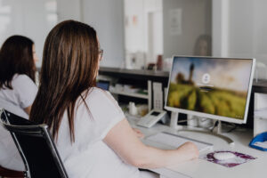 Bildschirm und Mitarbeiterin am Empfang